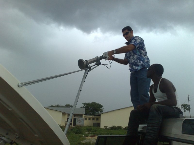 Engineers working with a satellite antenna on a vehicle